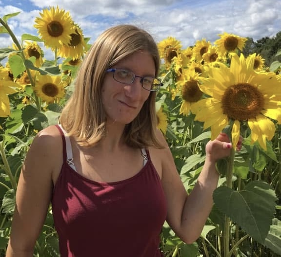 Jenny Dillon smiling in a field of sunflowers